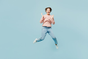 Fototapeta na wymiar Full body young excited overjoyed happy woman she wear beige knitted sweater casual clothes jump high look camera spread hands isolated on plain pastel light blue cyan background. Lifestyle concept.