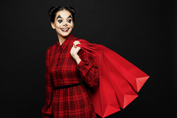 Young cool woman with Halloween makeup face art mask wear clown costume red dress hold shopping...