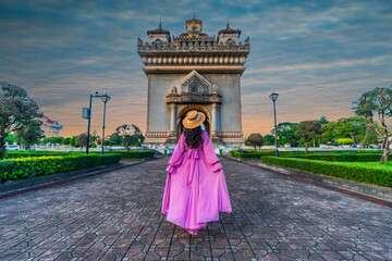 Asian girl in pink dress visits Patuxai at sunset in Vientiane, Lao PDR. - 661885371
