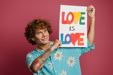 Handsome young man in funky shirt holding colorful banner against red background