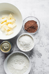 mise en place of ingredients for making chocolate cake, top view of sugar, eggs, cocoa powder, flour on a marble table, process of making chocolate cake