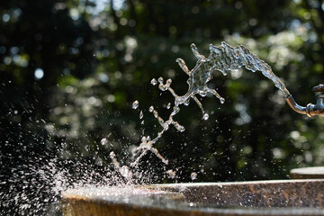 昼の公園の水道水の蛇口からの水飛沫の瞬間