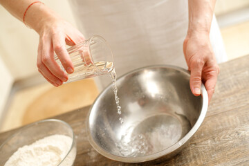 Young man kneading dough on wooden table. Males hands making bread on the kitchen. Baking concept.