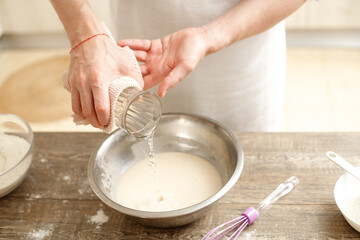 Young man kneading dough on wooden table. Males hands making bread on the kitchen. Baking concept.
