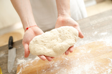 Young man kneading dough on wooden table. Males hands making bread on the kitchen. Baking concept.