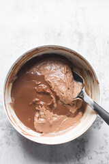Chocolate cake batter being mixed in a white bowl, folding cake batter in a white mixing bowl, the process of making chocolate cake