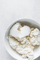 Strained Greek yogurt in a white ceramic bowl, process of making Greek yogurt, strained thick yogurt in white mixing bowl