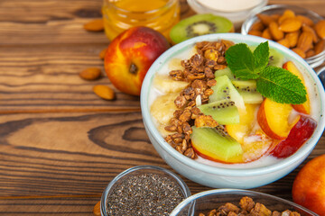 Bowl of granola with yogurt and fresh berries on a texture table. Yogurt berries, acai bowl, spirulina bowl. Healthy food, balanced breakfast. Strawberries, blueberries, kiwi, peach, almonds and chia.