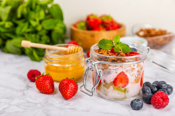 Bowl of granola with yogurt and fresh berries on a texture table. Yogurt berries, acai bowl, spirulina bowl. Healthy food, balanced breakfast. Strawberries, blueberries, kiwi, peach, almonds and chia.