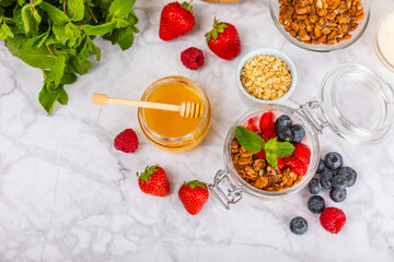 Bowl of granola with yogurt and fresh berries on a texture table. Yogurt berries, acai bowl, spirulina bowl. Healthy food, balanced breakfast. Strawberries, blueberries, kiwi, peach, almonds and chia.