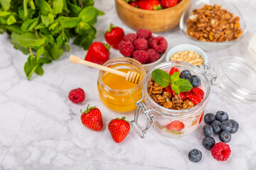 Bowl of granola with yogurt and fresh berries on a texture table. Yogurt berries, acai bowl, spirulina bowl. Healthy food, balanced breakfast. Strawberries, blueberries, kiwi, peach, almonds and chia.