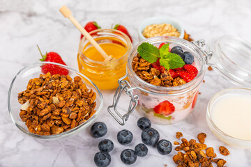 Bowl of granola with yogurt and fresh berries on a texture table. Yogurt berries, acai bowl, spirulina bowl. Healthy food, balanced breakfast. Strawberries, blueberries, kiwi, peach, almonds and chia.
