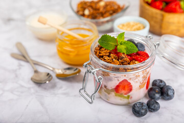 Bowl of granola with yogurt and fresh berries on a texture table. Yogurt berries, acai bowl, spirulina bowl. Healthy food, balanced breakfast. Strawberries, blueberries, kiwi, peach, almonds and chia.