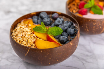 Bowl of granola with yogurt and fresh berries on a texture table. Yogurt berries, acai bowl, spirulina bowl. Healthy food, balanced breakfast. Strawberries, blueberries, kiwi, peach, almonds and chia.