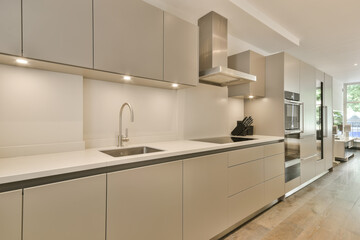 a modern kitchen with wood flooring and white cupboards on the wall behind it is an outdoor...