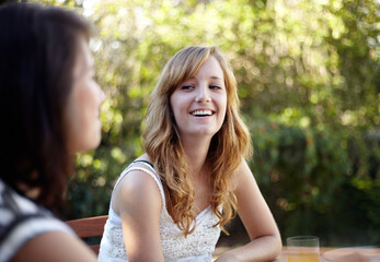 Happy, woman and friends outdoor in backyard with conversation and communication at home. Summer, laughing and funny joke with young people smile together in a garden with talking ready for bbq