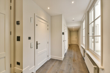 a long hallway with wood flooring and white trim on the walls, leading to an open door that leads to another room