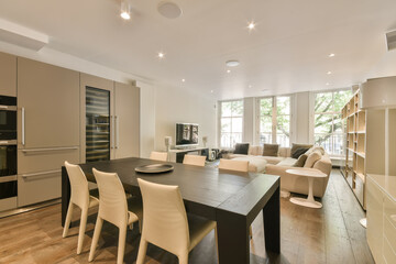 a kitchen and dining area in a modern apartment with wood flooring, white chairs and an oven on the wall