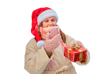 A happy woman stands with gifts and a phone in her hands at a Christmas tree in a snowy forest on New Year Eve, isolated on a white background