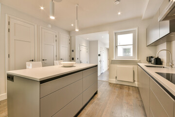 a modern kitchen with white cabinets and wood flooring in the middle of the room, looking towards...