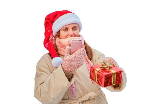 A happy woman stands with gifts and a phone in her hands at a Christmas tree in a snowy forest on New Year Eve, isolated on a white background