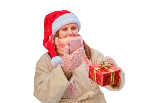 A happy woman stands with gifts and a phone in her hands at a Christmas tree in a snowy forest on New Year Eve, isolated on a white background