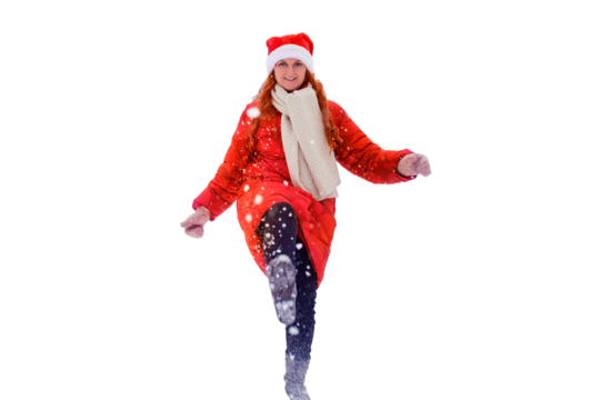 Young woman kicks snow with her foot on winter road in forest, isolated on a white background. Redhead woman on Christmas and New Year Eve walks outdoors in a red hat and jacket - Powered by Adobe