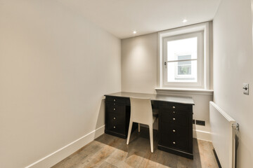 a desk in the corner of a room with white walls and hardwood flooring on the right side of the room