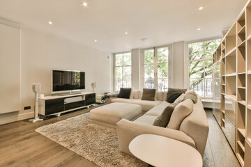 a living room with wood flooring and white walls, there is a tv on the wall in front of the couch