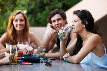 Friends, bar and drinks during conversation on the weekend for bonding, happiness and social. Table, alcohol and people, men or women speaking at an outdoor restaurant for a group chat or drinking