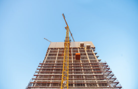 Looking up at the construction site of a high-rise building with a yellow crane