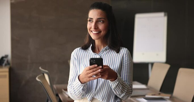 Beautiful Brazilian businesswoman use smartphone in office. Successful businesslady chatting online, share messages, solve business by e-mailing feel satisfied, check calendar, writes in organizer app