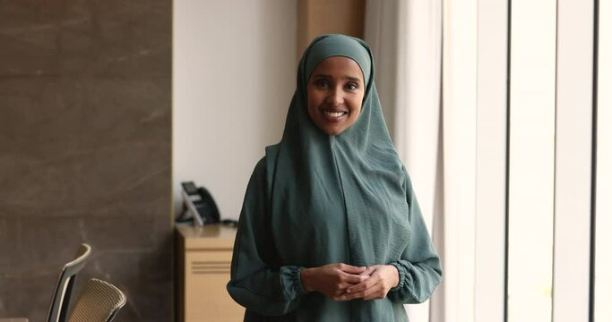 Beautiful young Somalian businesswoman wear hijab posing in modern office. Thoughtful pensive Muslim female office employee looking out window think of future project, planning project. Aspirations