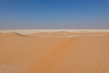 Panorama of small desert dunes with red sand on the limestone horizon.