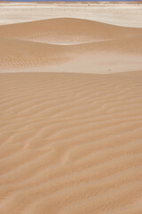Panorama of small dunes with red sand and vertical streaks on the limestone horizon.