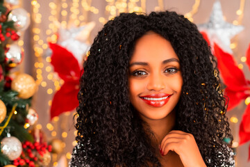 Christmas portrait of a young black woman with long curly hair against a background of a Christmas tree