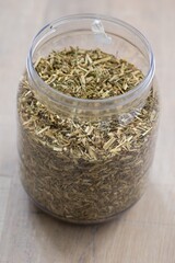 A closeup portrait of a plastic jar or pot full of fresh dried loose viola tricolor leaves to set a fresh cup of tea. The herbs are ready to be used in a relaxing warm beverage for some zen time.