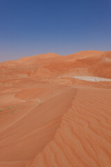 Fototapeta na wymiar Ridge of the red desert dune in the background a white car and high dunes.