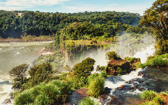 Iguazu (Iguacu) natural waterfall in greenery rainforest in Argentina, sunny summertime day. View of powerful falls with sunny cascade waterfalls landscape. World nature concept. Copy ad text space
