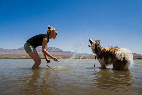 A woman splashes in the water with her dog at Caballo Lake State Park, New Mexico