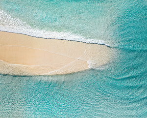 Aerial landscape of a beach at sunrise with stunning blue water and gentle waves on white sand