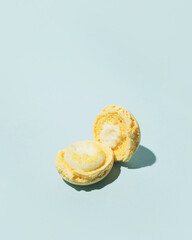 Open creamy macaron cookie, vanilla flavor, minimal dessert composition, pastel blue background.