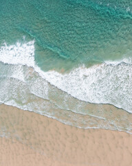 Aerial view of a stunning beach and white sand near the ocean with gentle wave