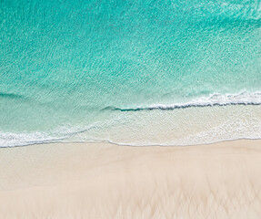 Aerial landscape of a beach at sunrise with stunning blue water and gentle waves on white sand