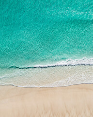 Aerial view of a stunning beach and white sand near the ocean with gentle wave