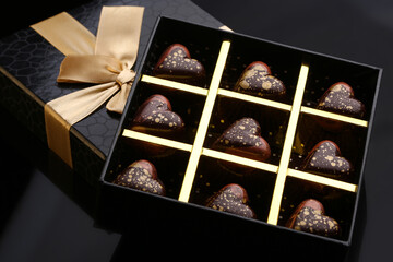 Heart shaped painted luxury handmade bonbons in a gift box on a black background. Chocolates for...