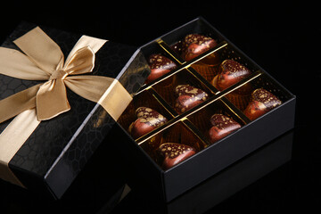 Heart shaped painted luxury handmade bonbons in a gift box on a black background. Chocolates for...