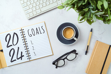 New Year 2024 goals and resolution business concept with notebook, coffee cup, computer keyboard and plant on modern office desk. Top view, flat lay