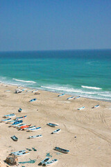 Vertical photo from above fishermen's boats on the beach on the horizon blue green sea. Oman.