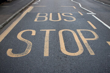 Yellow road markings "Bus Stop" UK painted on a asphalt road - Powered by Adobe